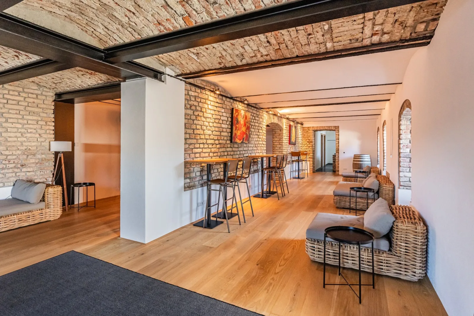 Die Lounge der Brennerei Pentenried mit Stehtischen und Sitzgruppen unter dem Ziegelgewölbe